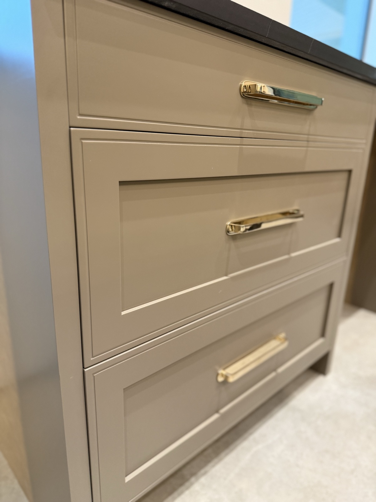 Close-up of greige shaker drawer fronts with polished brass pulls